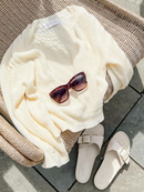Close-up of a daffodil yellow sweater with a textured knit, styled with white high-waisted jeans and delicate gold jewelry.