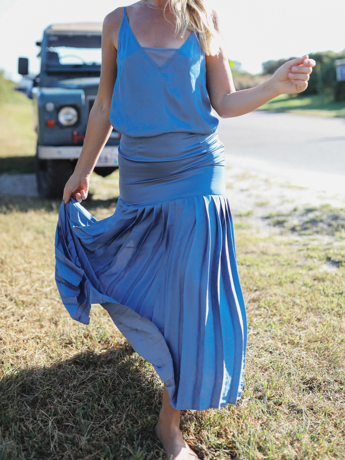 A detailed close-up of a flowing blue pleated skirt paired with a coordinating cami, showcasing movement and texture.
